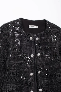 Detailaufnahme der schwarzen Tweed-Paillettenjacke mit Silberknöpfen und Etikett