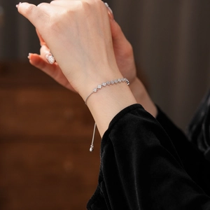 Detail of silver clover flower bracelet with zircons worn on wrist with adjustable chain