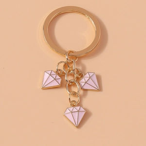 Detail of gold metal keychain with three pink diamond-shaped pendants and a sturdy split ring