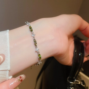 Detail of silver bracelet with marquise green zircons and square clear crystals on wrist
