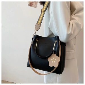 Detail der schwarzen PU-Leder-Eimertasche mit gestreiftem Gurt und Metallringgriff