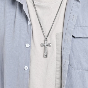 Hip hop silver stainless steel cross pendant necklace with textured finish worn by a model