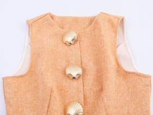 Détail de la texture tweed et boutons dorés en forme de coquillage sur un gilet orange