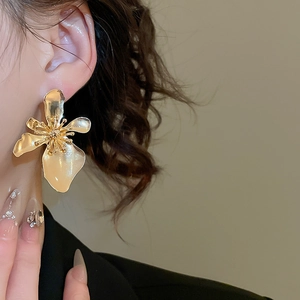 Close-up of elegant golden flower stud earring worn by a model with a polished finish