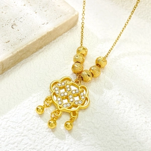 Macro shot of gold-plated lock pendant featuring micro-set zircons and dangling beads