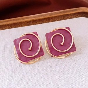 Detail shot of vintage square purple earrings with gold spiral accents on soft fabric