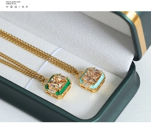 Detail of square zircon pendants with green and light blue enamel on gold titanium necklaces