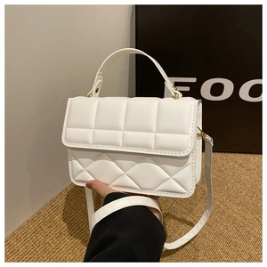 Detail of white quilted handbag with gold hardware and elegant top handle strap
