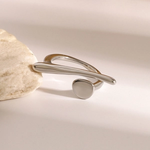 Detail shot of a polished irregular silver ring resting on natural stones for a modern look