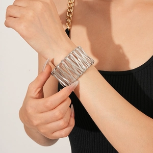 Gros plan d'un bracelet manchette argenté en fil métallique au poignet, style industriel