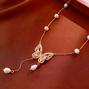 Macro detail of gold-plated butterfly necklace with zircons and pearls on velvet