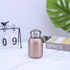 Detail of rose gold mini vacuum flask with foldable metal handle on marble surface