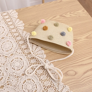 Detail view of straw woven mini bag with colorful pom poms on light wood surface