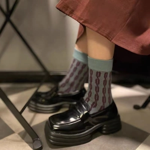 Gros plan de chaussettes en coton gris à motifs rouges portées avec des mocassins