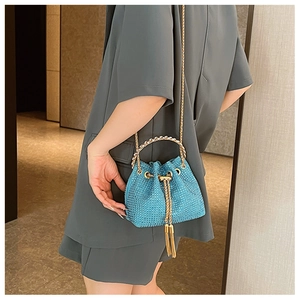 Detail of blue rhinestone bucket bag with gold ring handle and tassel drawstring