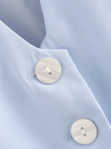 Détail du tissu en sergé bleu clair et bouton blanc sur un débardeur court Y2K pour femme