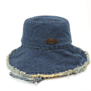 Fashionable dark blue denim bucket hat with frayed edges and metal label on white background