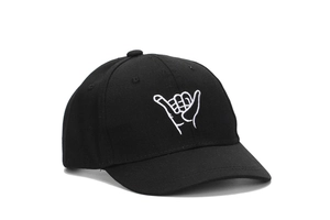 Close-up of white Shaka Sign embroidery on a black cotton six-panel baseball cap