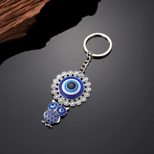 Dettaglio portachiavi gufo con cristalli blu e ciondolo occhio di Allah su metallo