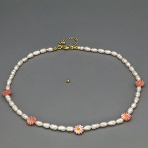 Detail of freshwater baroque pearls with pink daisy charm and golden lobster clasp