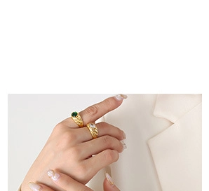 Detailed view of gold rings featuring emerald green and clear white gemstones on model