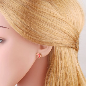 Detailed view of crescent moon stud earrings with red enamel and gold-plated beaded edges
