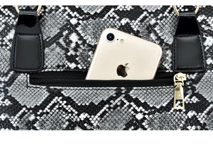 Detail of snake print texture and zipper pocket on shoulder bag with gold hardware