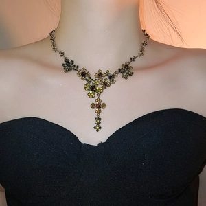 Close-up of vintage flower necklace with red and green rhinestones worn by a model