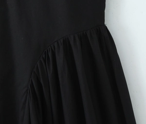 Detailed close-up of pleated black fabric texture and stitching on an evening maxi dress