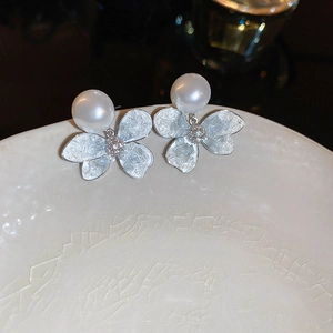 Macro detail of elegant flower stud earrings with white pearl and icy textured petals