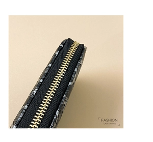 Detailed close-up of golden metal zipper and black embossed texture on women's purse