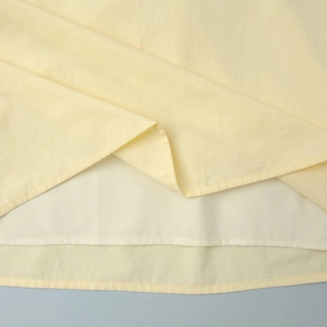 Détail de l'ensemble jaune clair montrant le tissu tissé fin et l'ourlet à double couche