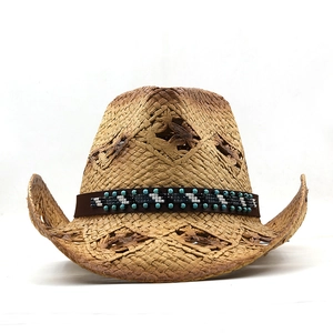 Détail d'un chapeau de cowboy en paille tressée avec motifs ajourés et perles ethniques
