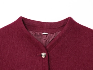 Dettaglio di un cappotto di lana bordeaux con un grande bottone metallico sferico argento