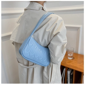 Close-up of light blue shoulder bag featuring unique pleated design and faux leather texture