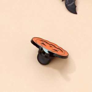 Detailed view of enamel pumpkin brooch with black rubber clutch for Halloween party