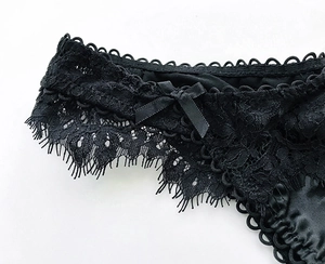 Dettaglio ravvicinato di pizzo nero elegante e tessuto in raso con un fiocco delicato