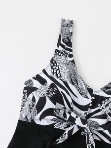 Detailed view of the bow tie neckline and abstract vine print on this black tankini top