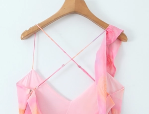 Detail of pink floral dress featuring delicate ruffles and crisscross spaghetti straps