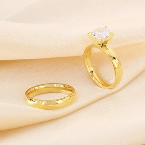 Detail of gold-plated wedding ring set featuring a four-prong solitaire and a plain band