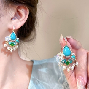 Detail of vintage bohemian drop earrings with turquoise stones and pearl tassels