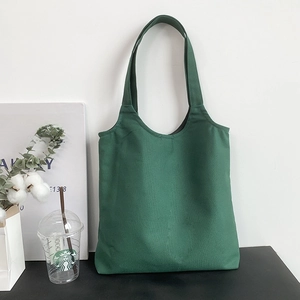 Close-up of a minimalist dark green canvas tote bag with reinforced handles for custom logo