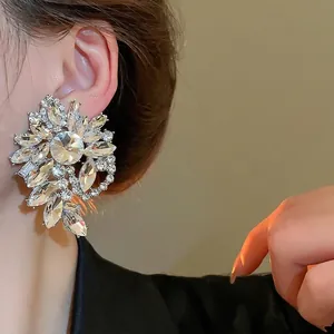 Elegant silver flower stud earrings with sparkling crystals shown on a model