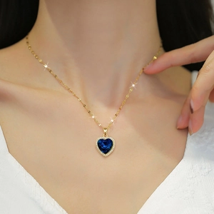 Elegant gold titanium necklace with a heart-shaped blue gemstone and sparkling crystals
