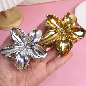 Elegant gold and silver flower hair claw clips held by hand for hair styling