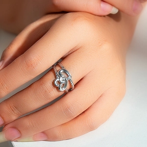 Detail of silver intertwining hearts ring with rope texture band on model hand