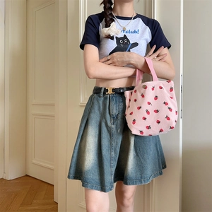 Détail du sac à main en velours côtelé rose avec imprimé fraise porté par un mannequin