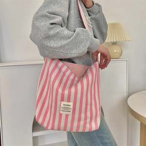 Dettaglio della borsa tote in tela a righe rosa e beige indossata da una modella