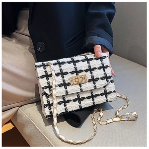 Close-up of black and white tweed chain bag with gold hardware worn by a model