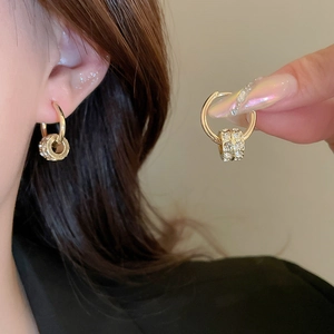 Close-up of golden hoop earrings with pavé crystal charms shown on model and held by hand